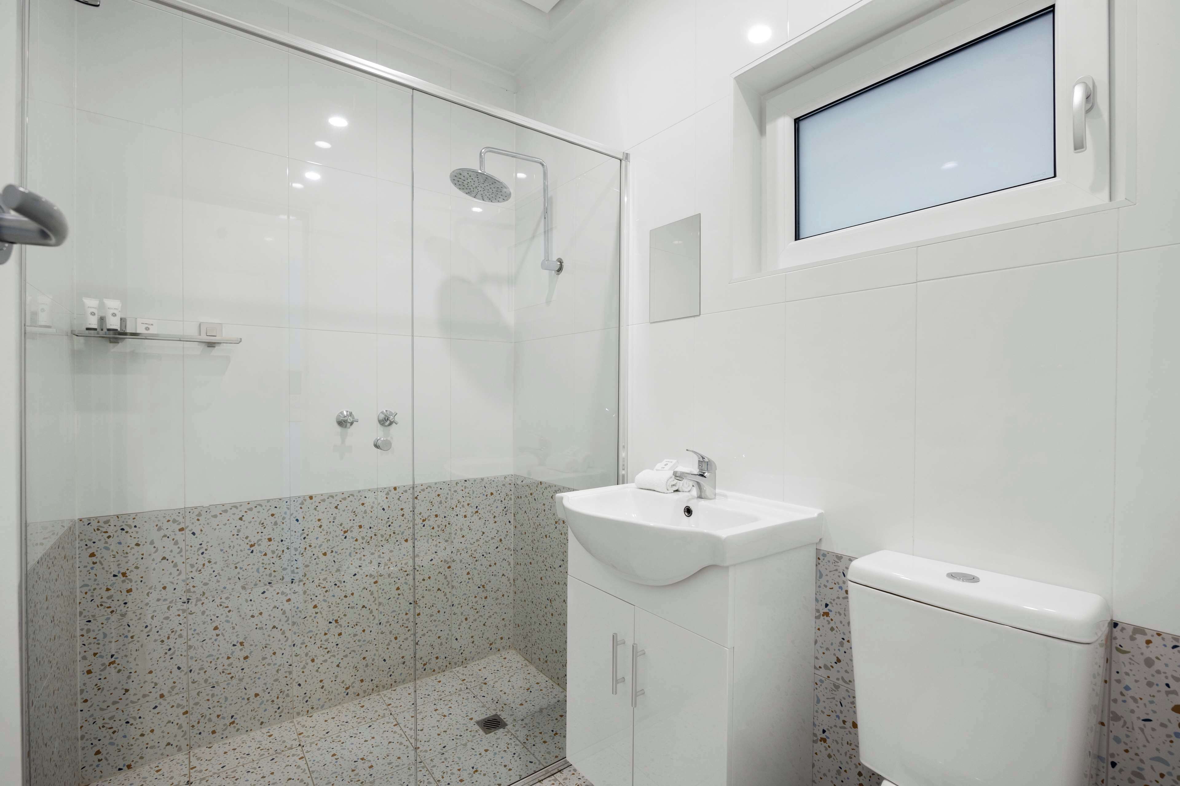 Une salle de bain moderne avec une douche à parois de verre, un lavabo blanc et des toilettes.