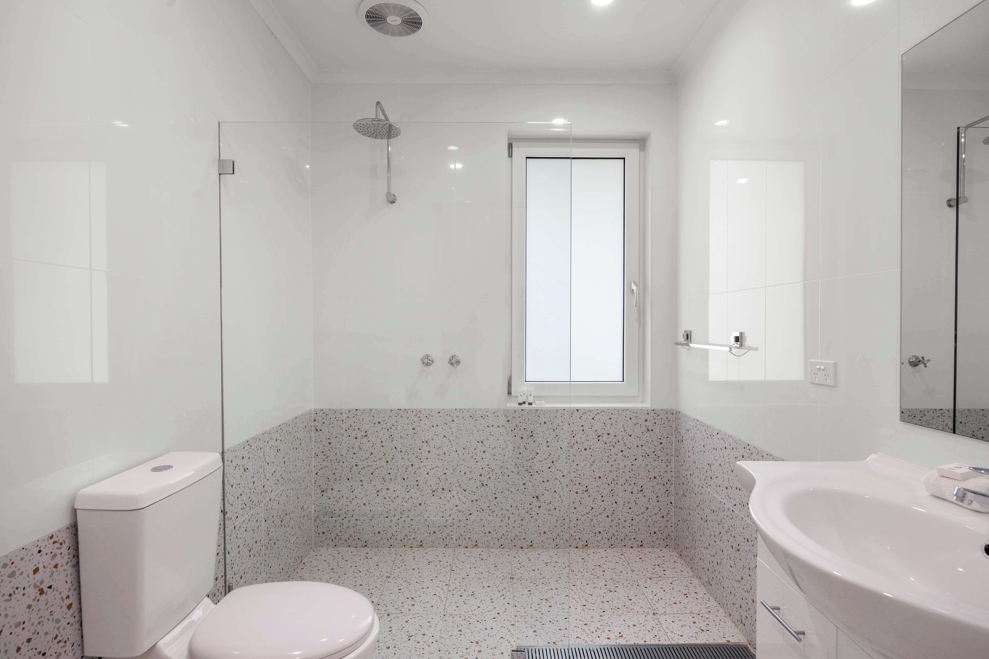 A modern bathroom with a toilet, shower, and sink.