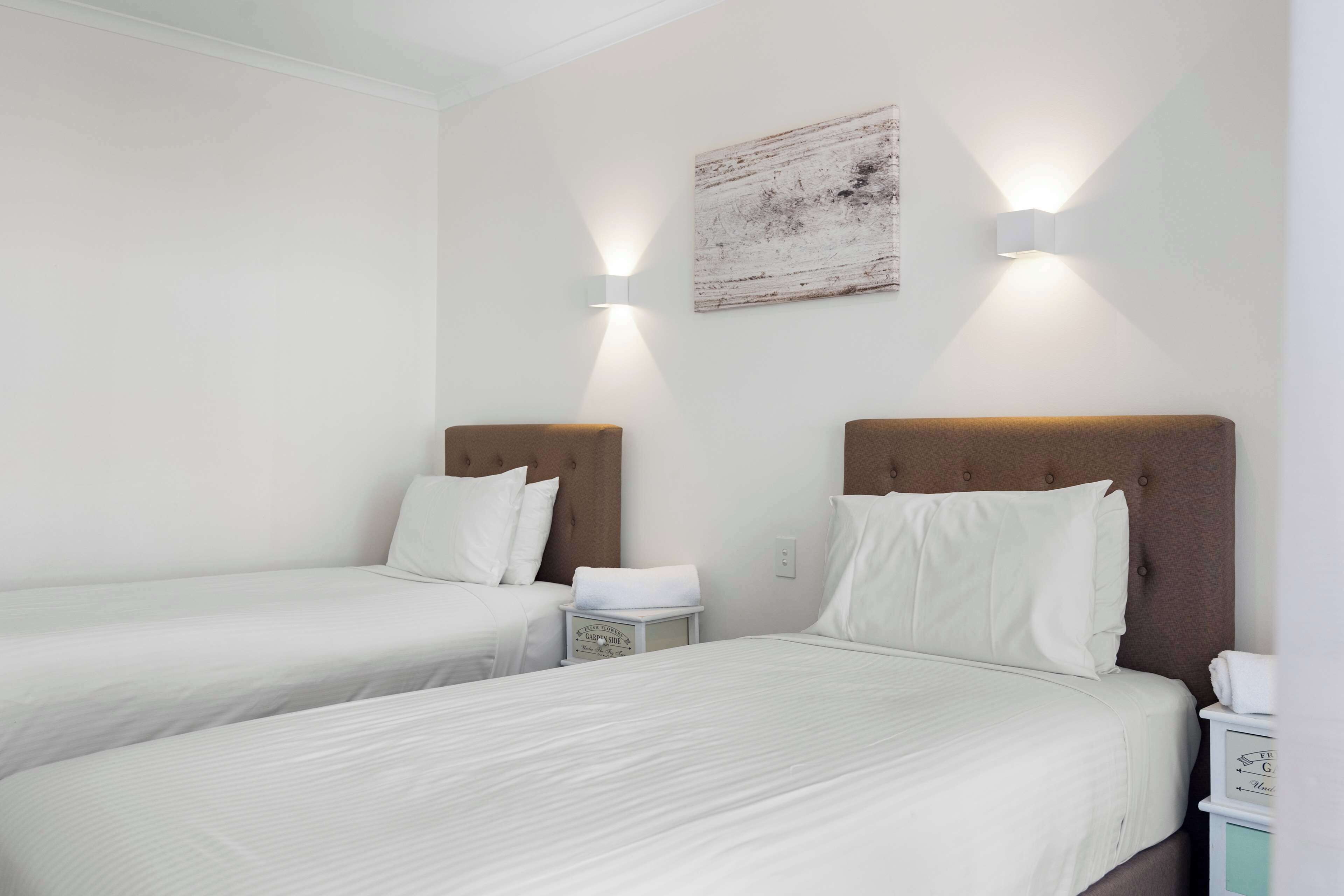 Ein Hotelzimmer mit zwei Einzelbetten, einem Nachttisch mit Lampe und einem Wandbild.