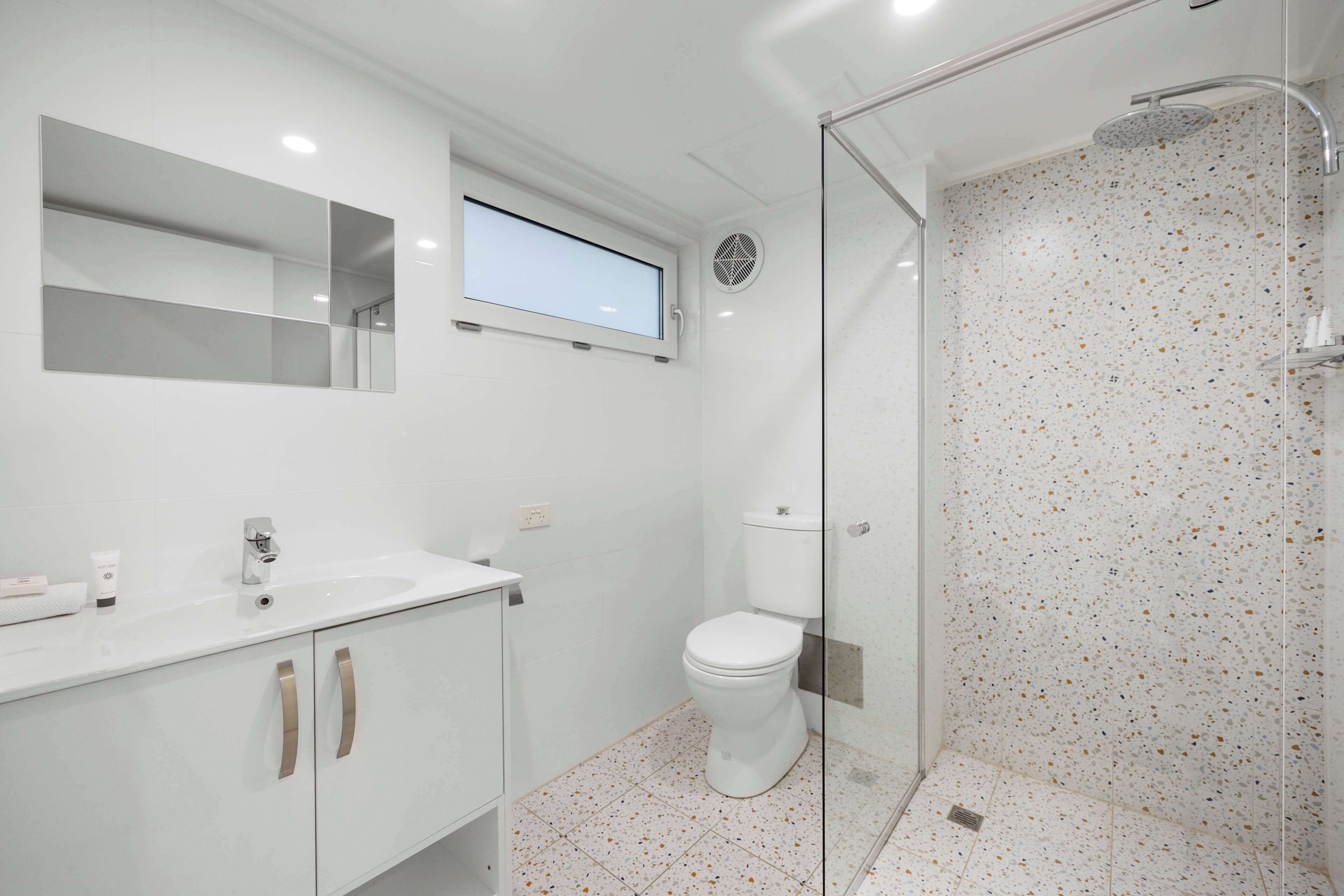 Ein modernes Badezimmer mit einem weißen Waschbecken, einer Toilette und einer Duschkabine.