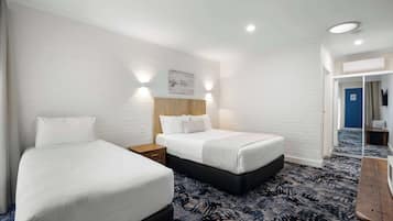 Une chambre d’hôtel avec deux lits, une tête de lit en bois, une moquette à motifs et une porte bleue.