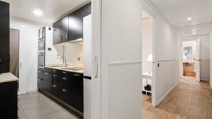 Una cocina moderna con armarios oscuros, un refrigerador blanco y piso de madera.