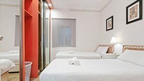 Habitación de hotel con dos camas, una pared roja, una ventana y un cuadro enmarcado.