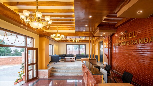 A hotel lobby with a reception desk, seating area, and a chandelier.