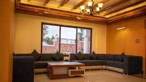 A modern living room with a sectional sofa, a coffee table, and a large window offering a view of a brick building.