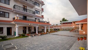 A multi-story hotel with a covered outdoor area, potted plants, and a tiled courtyard.