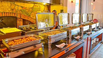 Un bufé con diversas opciones de comida, un horno de ladrillo y un letrero para la entrada de mujeres.