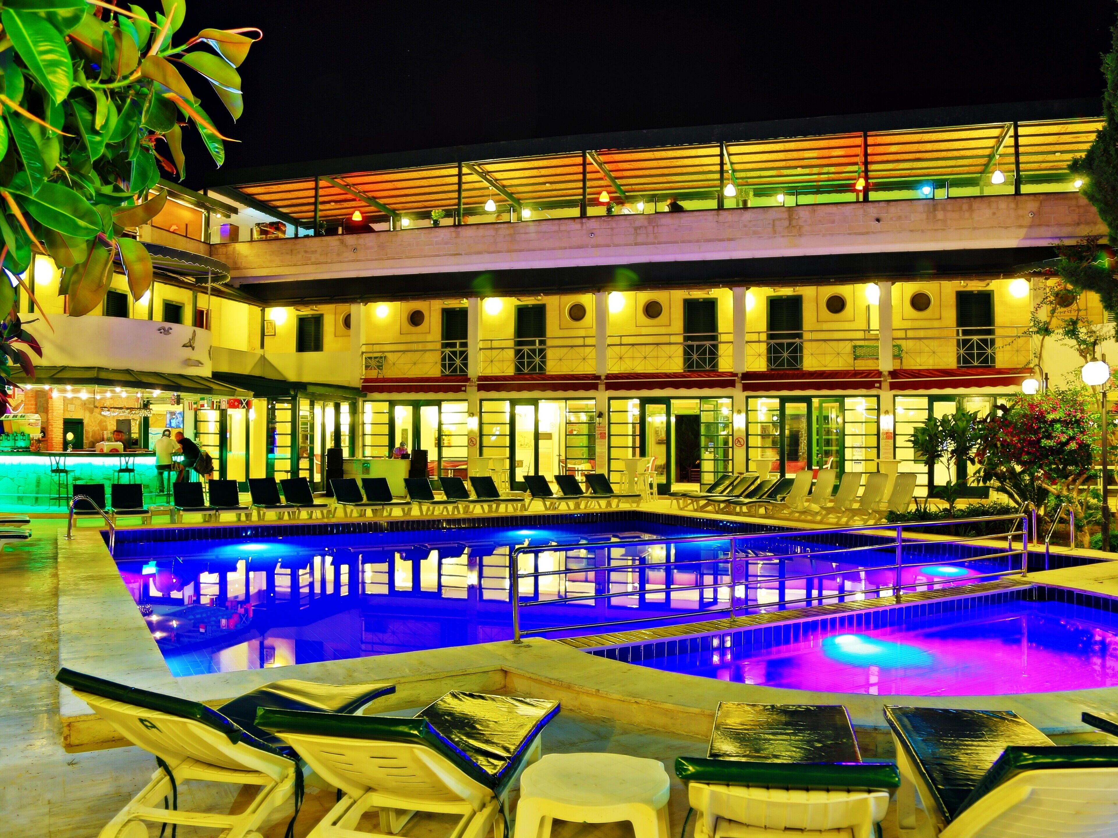 A hotel with a swimming pool, lounge chairs, and a bar area.