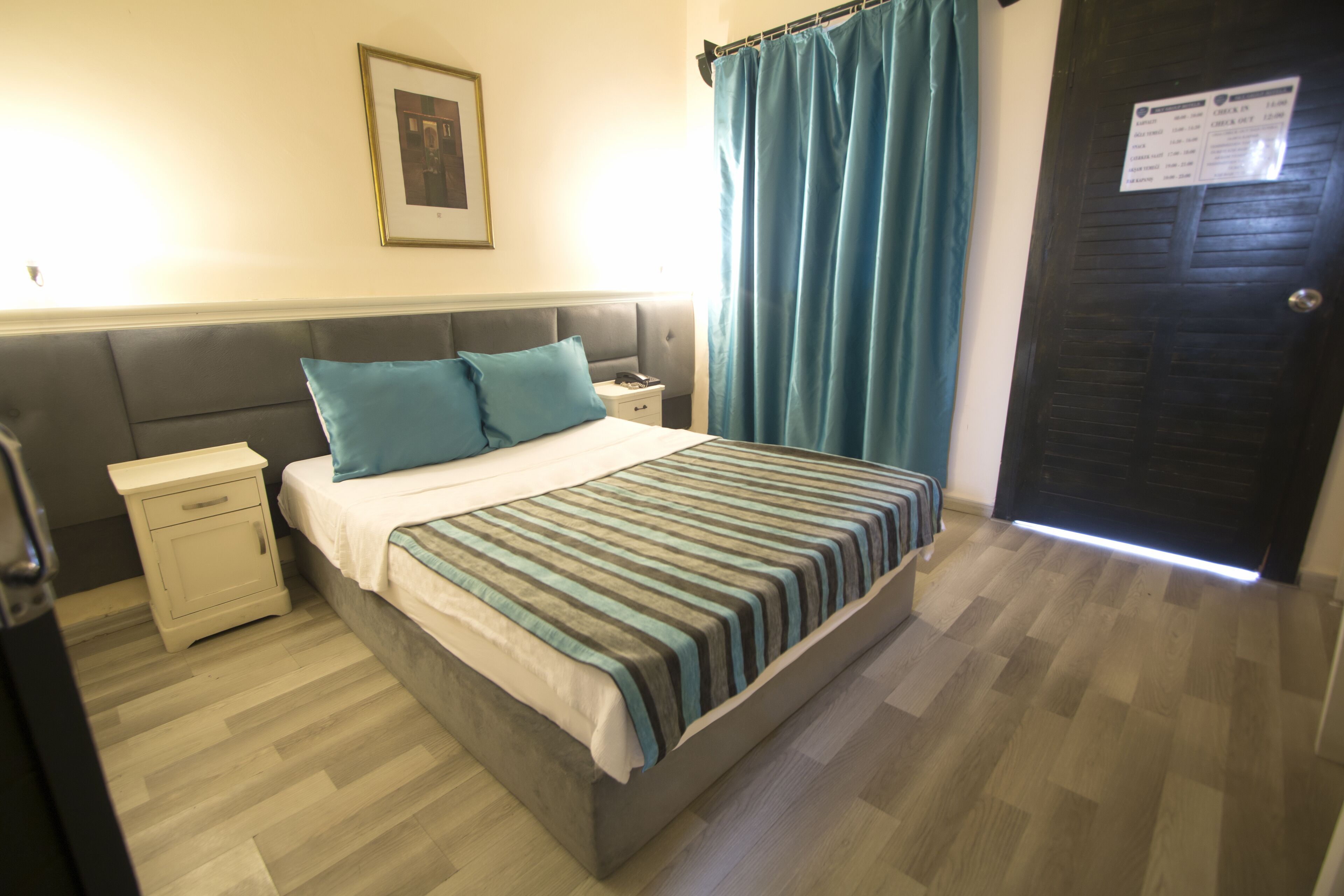 A bedroom with a bed, nightstand, and a door with a sign.