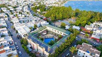 A coastal hotel with a swimming pool, solar panels, and a view of the sea.