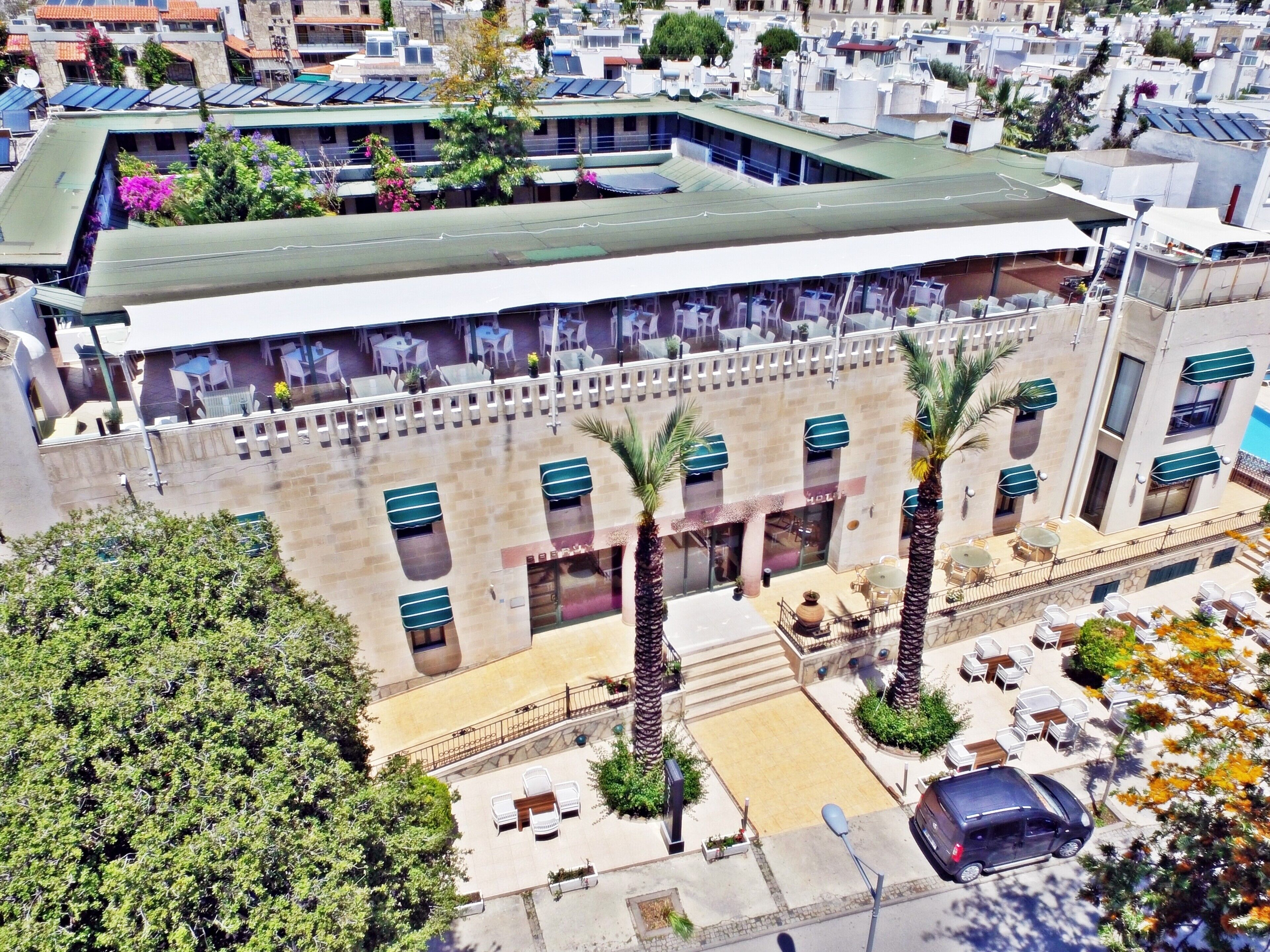 Un edificio de varios pisos con techo plano, zona de estar al aire libre y palmeras.