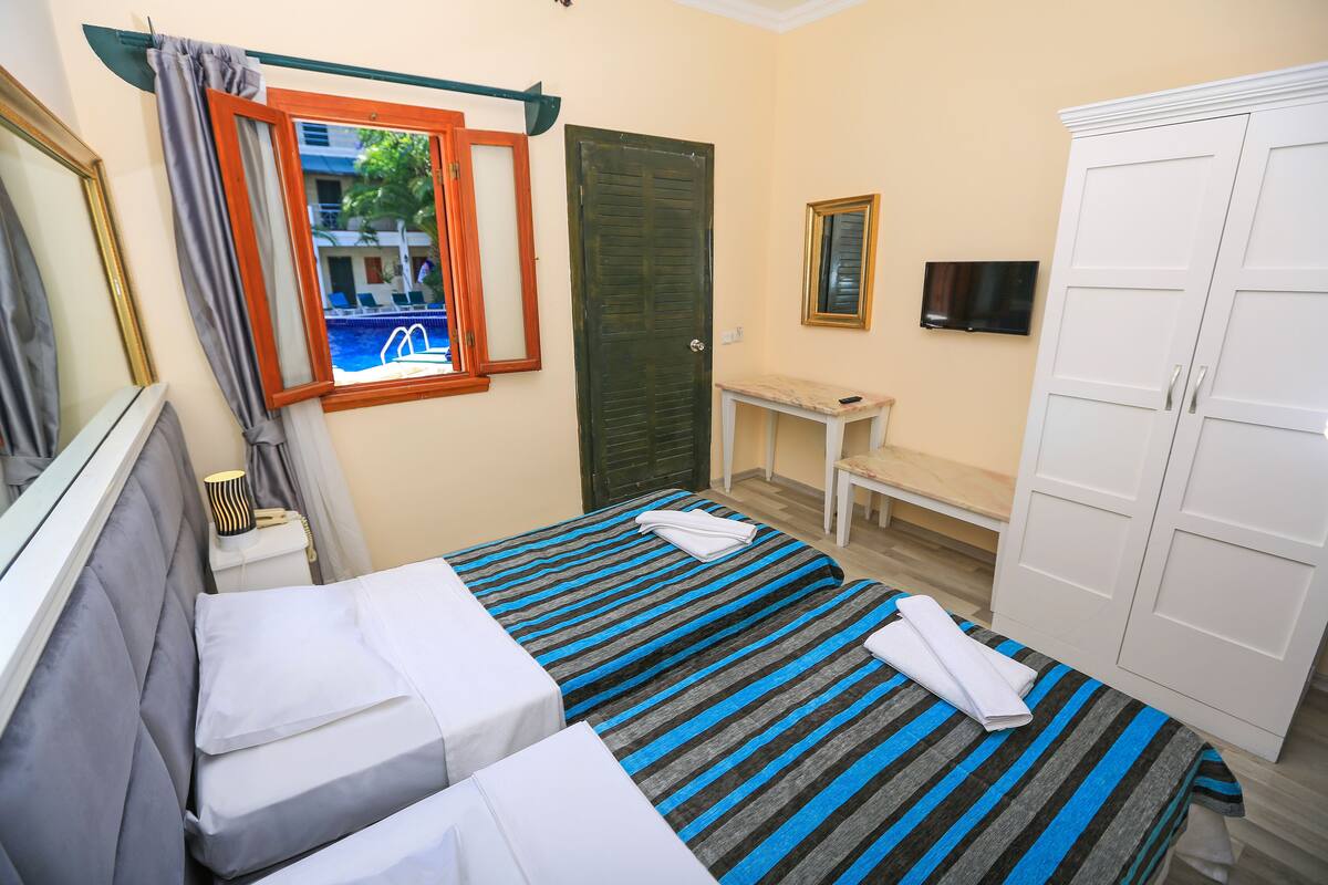 A hotel room with two beds, a desk, a TV, and a wardrobe.