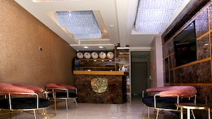 Una zona d'entrada amb un taulell de marbre, rellotges i una recepció.
