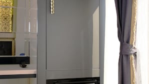 Cuina amb forn integrat i microones, finestra amb cortines i taula petita amb una tassa.