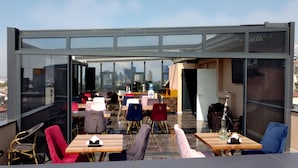 Un café a la terrassa amb una estructura de vidre, amb vistes a la ciutat.