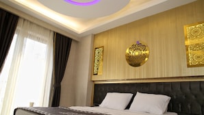 Habitació d'hotel amb un llit gran, una tauleta de nit amb un telèfon i panells decoratius a la paret.