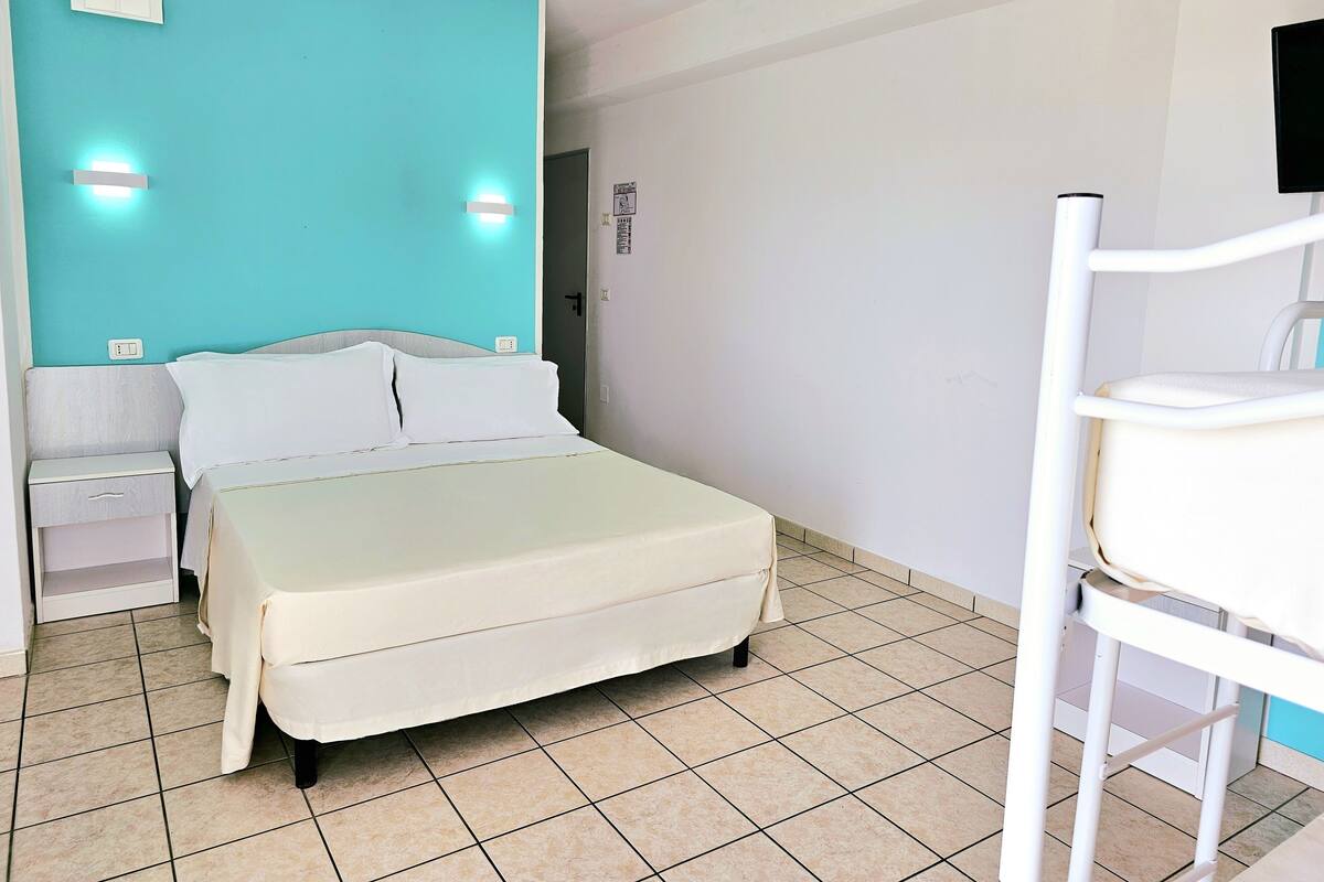 Ein Hotelzimmer mit einem Bett, Nachttischen, einem Sessel und einem an der Wand befestigten Fernseher.