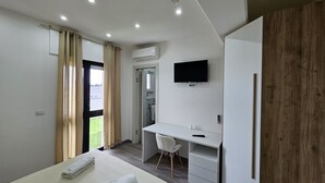 Ein modernes Hotelzimmer mit Bett, Schreibtisch, Stuhl, Fernseher und Kleiderschrank.