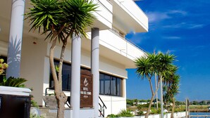 Ein modernes Hotel mit weißer Fassade, Palmen und blauem Himmel.