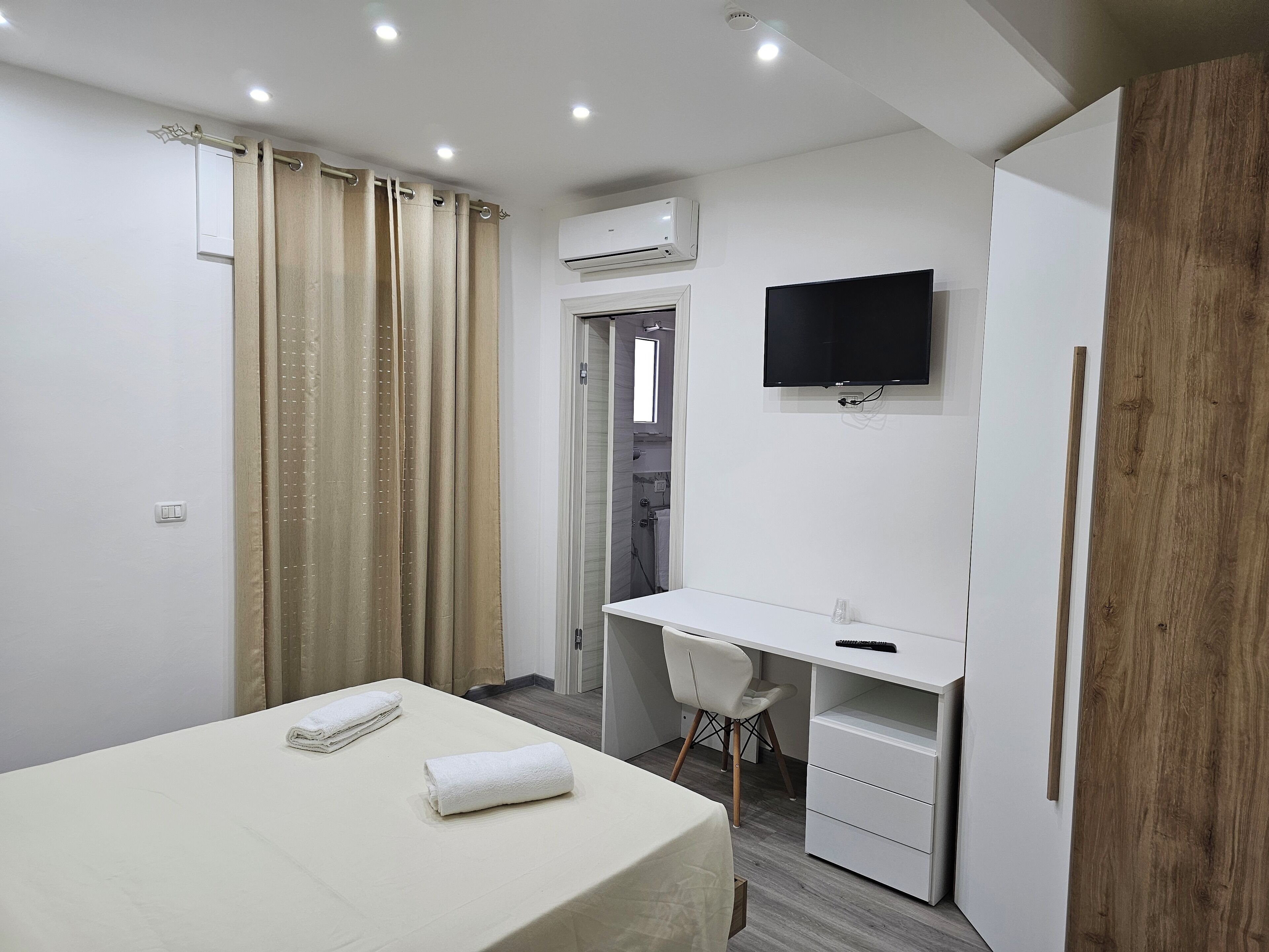 A modern hotel room with a bed, a desk, a chair, and a TV.