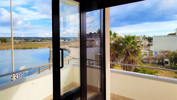 Ein Balkon mit Blick auf einen Fluss, Palmen und entfernte Gebäude.