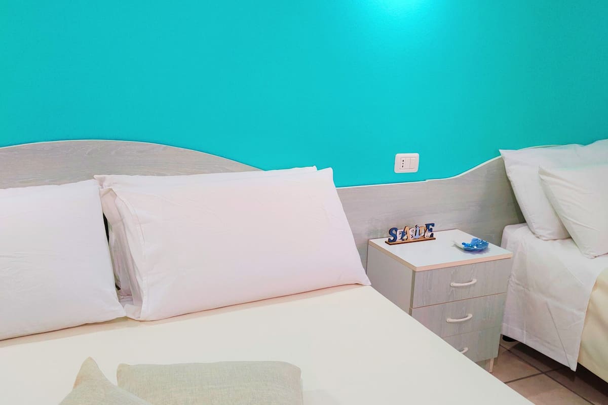 Ein Hotelzimmer mit Bett, Kissen, Nachttisch und Beistelltisch.