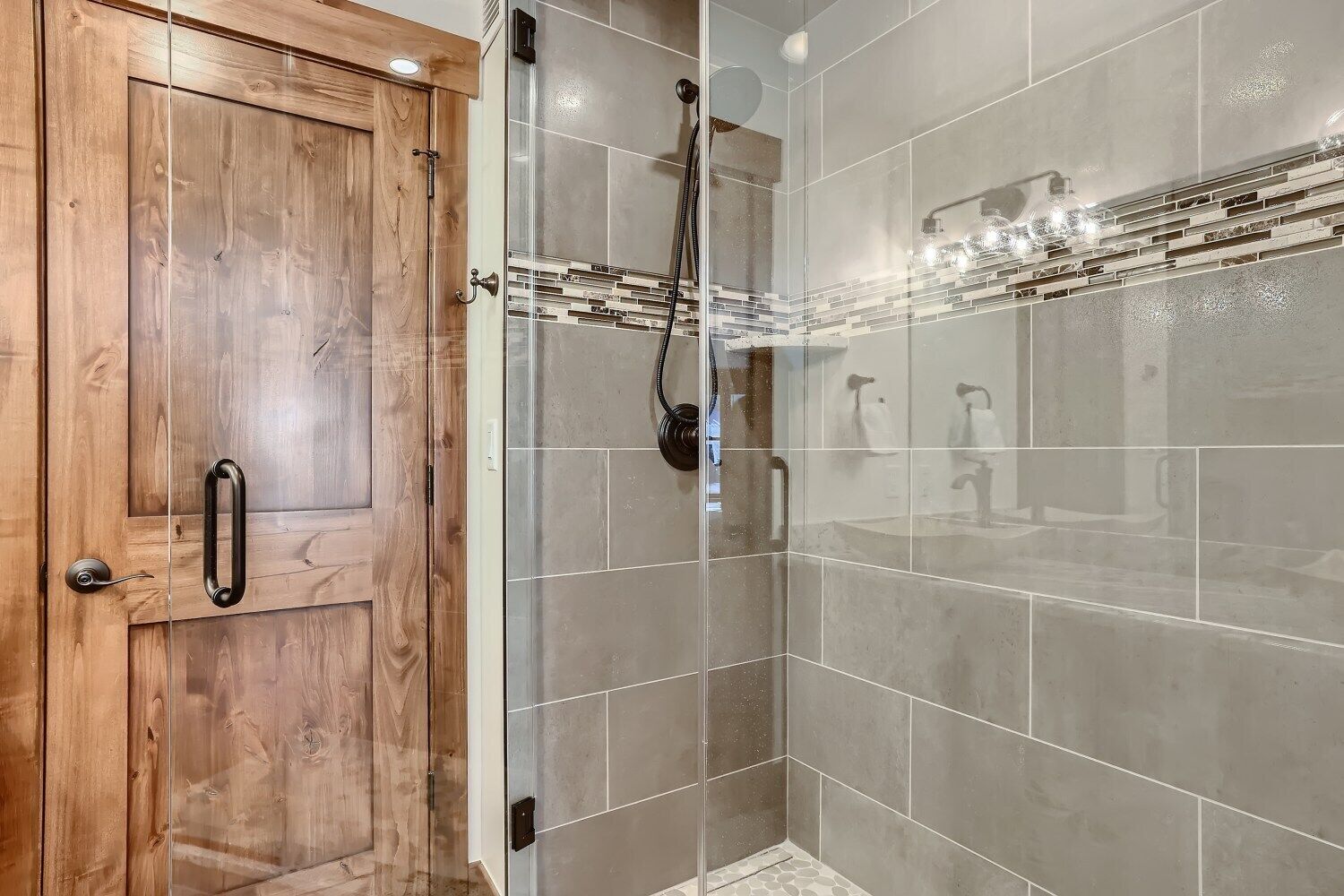 A shower area with a wooden door and tiled walls.