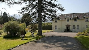 A large, single-story building with a symmetrical facade, a central entrance, and a paved driveway leading to the entrance. - Isle of Skye Guest house (Kyleakin)