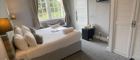 A bedroom with a bed, a TV mounted on the wall, and a wardrobe.