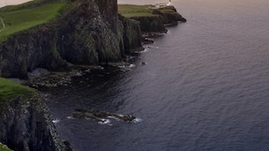 A coastal landscape with a grassy cliff, a lighthouse, and the ocean. - Isle of Skye Guest house (Kyleakin)