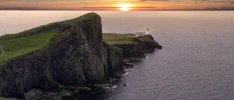 A coastal landscape with a grassy cliff, a lighthouse, and the ocean.