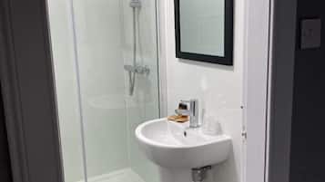 Un baño moderno con cabina de ducha de vidrio, un lavabo blanco y un espejo.