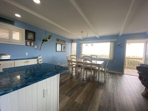 A spacious kitchen with a blue countertop, wooden cabinets, and a dining area with a table and chairs.