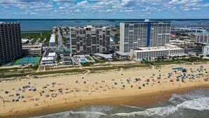 Un hotel frente a la playa con varios edificios altos, una playa de arena y vistas al océano.