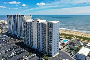 A high-rise hotel with multiple floors, a parking lot, and a beach view. - Luxury, newly renovated 2 bedroom condo with a beautiful oceanfront balcony! (Ocean City)