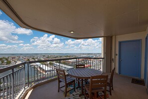 A balcony with a table and chairs, overlooking a cityscape and water. - Luxury, newly renovated 2 bedroom condo with a beautiful oceanfront balcony! (Ocean City)