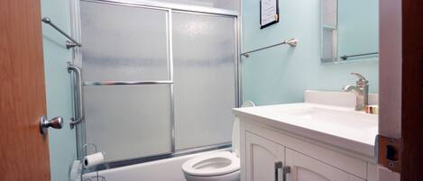 A bathroom with a shower, toilet, and sink.