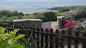 A stone staircase leading to a scenic overlook with a view of the sea and hills. - Stonecroft (Helston)