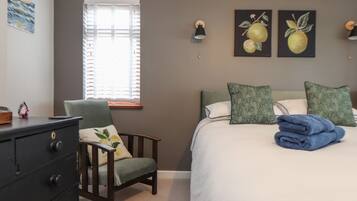 A bedroom with a bed, a chair, a dresser, and artwork on the walls.