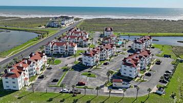 A coastal hotel with multiple buildings, a parking lot, and a view of the ocean.