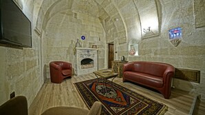 Une pièce aux murs de pierre, avec une cheminée, des canapés en cuir et un tapis à motifs.