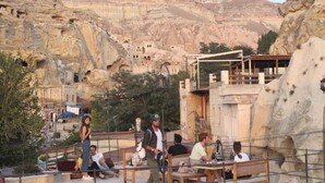 Une terrasse dotée de sièges extérieurs, offrant une vue sur un paysage montagneux parsemé d’anciennes formations rocheuses.
