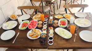 Une table à manger dressée avec différents plats, notamment des fruits, des légumes et des condiments.