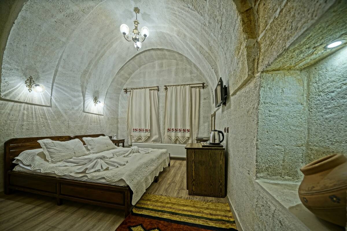 A bedroom with a wooden bed, a nightstand, a radiator, and a chandelier.