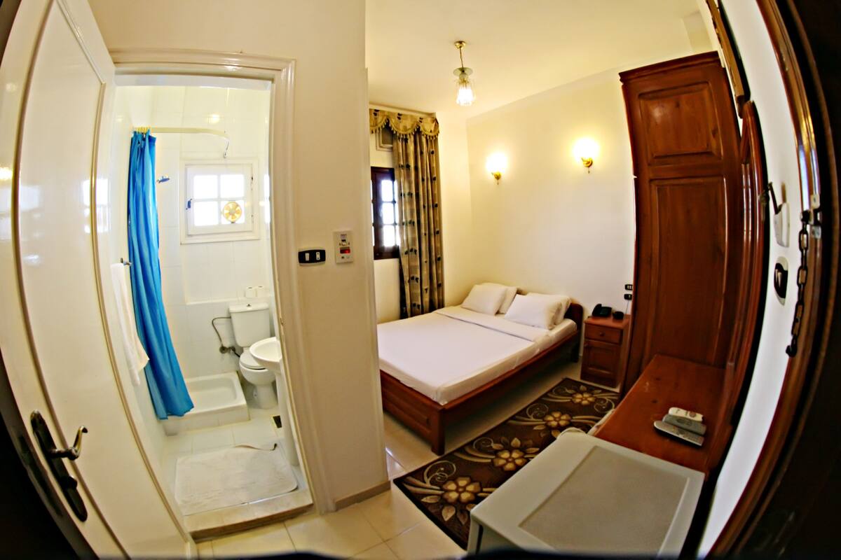 A bedroom with a bed, bedside table, and a wooden wardrobe.