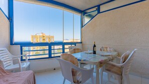 Een balkon met een tafel gedekt voor twee personen, stoelen, een fles wijn en uitzicht op gebouwen.