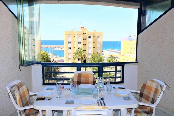 A balcony table set with plates, glasses, and cutlery, overlooking a coastal area with buildings and the sea. - 25D TB 2nd line of the beach with sea views (Calpe/Calp)