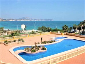 A swimming pool with a view of the sea and a distant mountain. - Apartamento 1E 2 Dormitorios (Calpe/Calp)