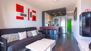 Un salon moderne comprenant un canapé, une table basse et un coin cuisine avec un bar pour prendre les repas.