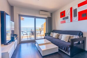 Un salon moderne avec un canapé, une table basse, un téléviseur et un balcon offrant une vue agréable.